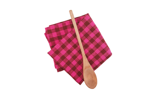 Pink and brown checkered towel with a wooden spoon on a white background