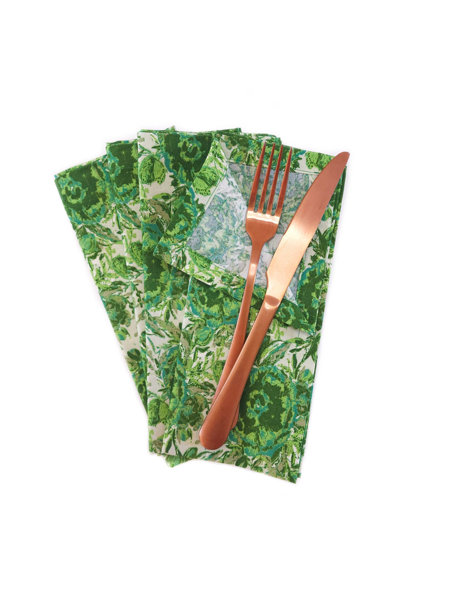 Set of green patterned napkins with a copper fork and knife on a white background