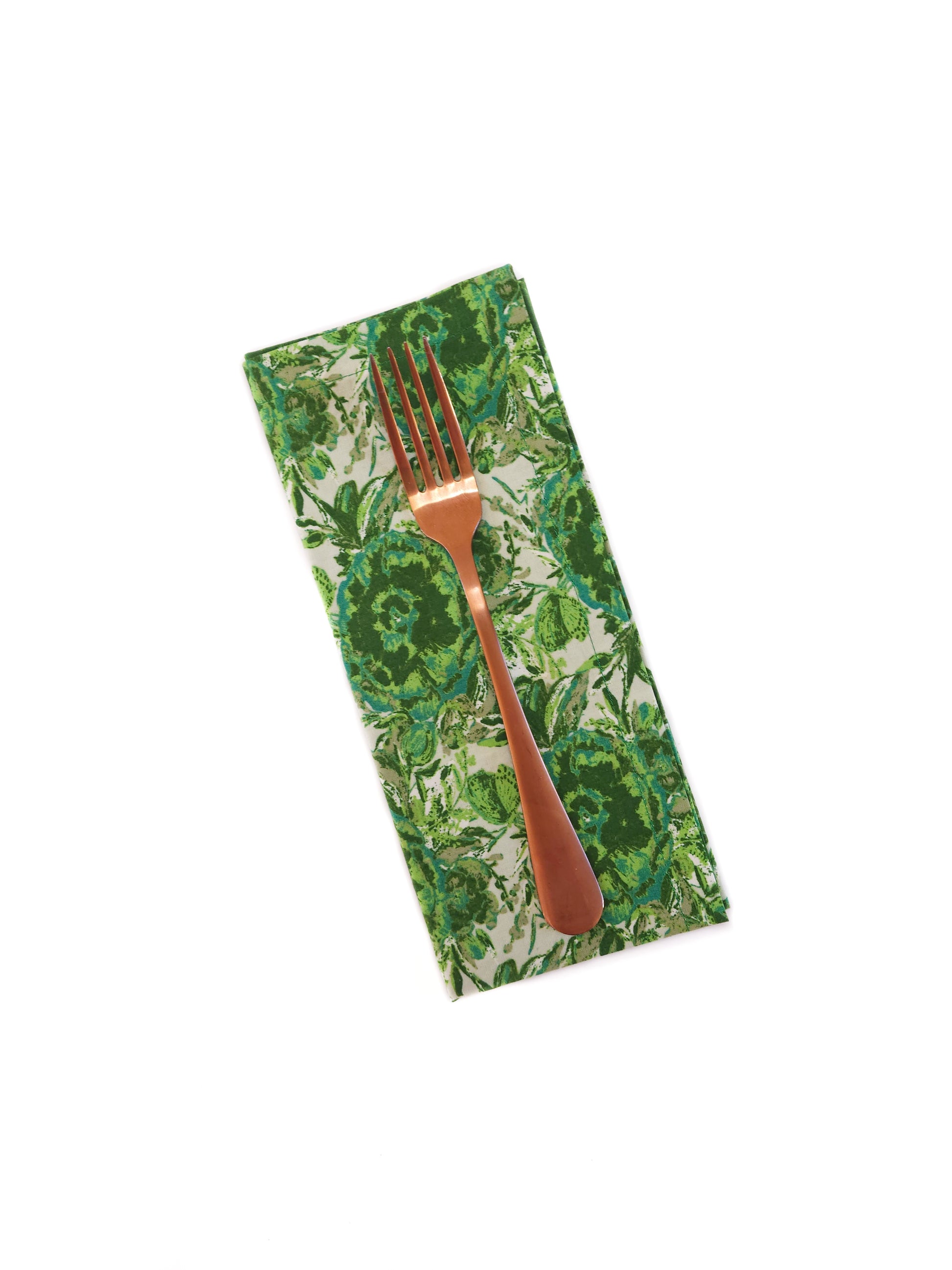 Green floral-patterned napkin with a copper fork on a white background