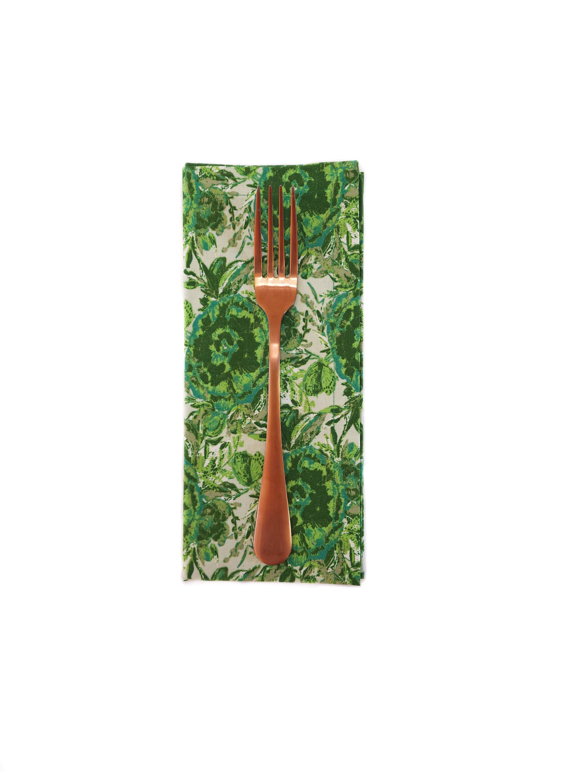 Bronze fork on a green leaf-patterned napkin against a white background