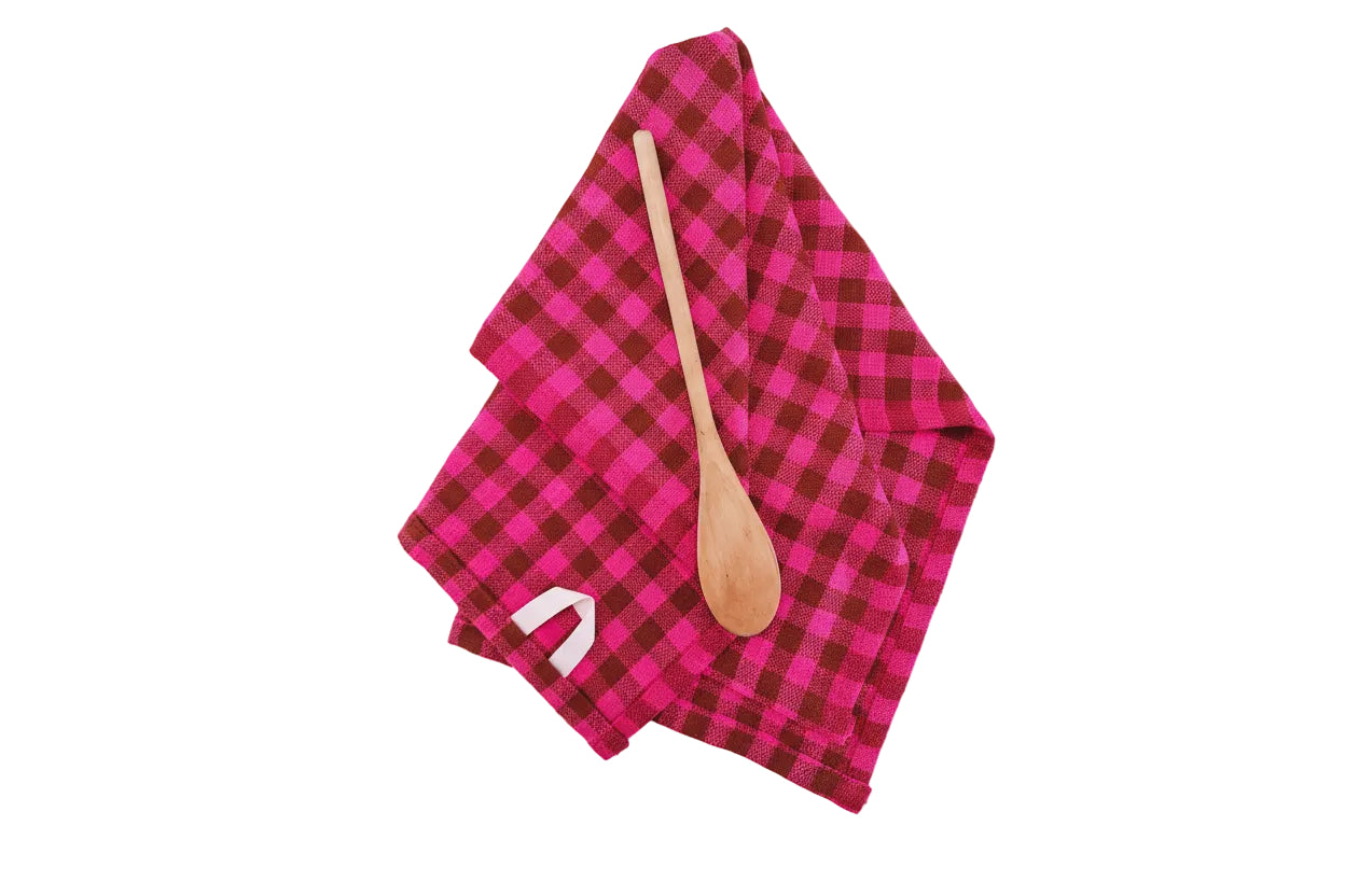 Pink and brown checkered towel with a wooden spoon on a white background.